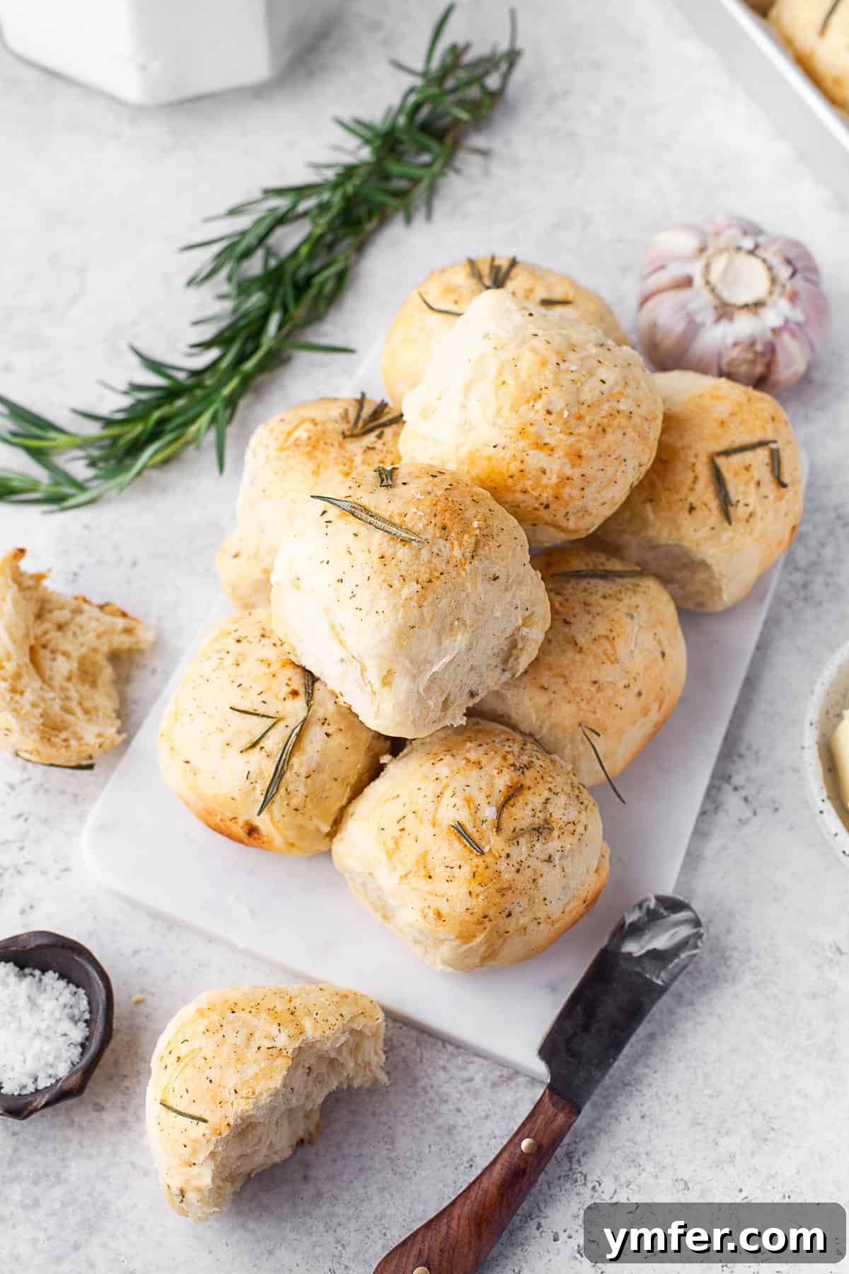 Warm Garlic Herb Rolls 2 Freshly baked Garlic Herb Dinner Rolls served on a rustic wooden board, ready to be enjoyed.