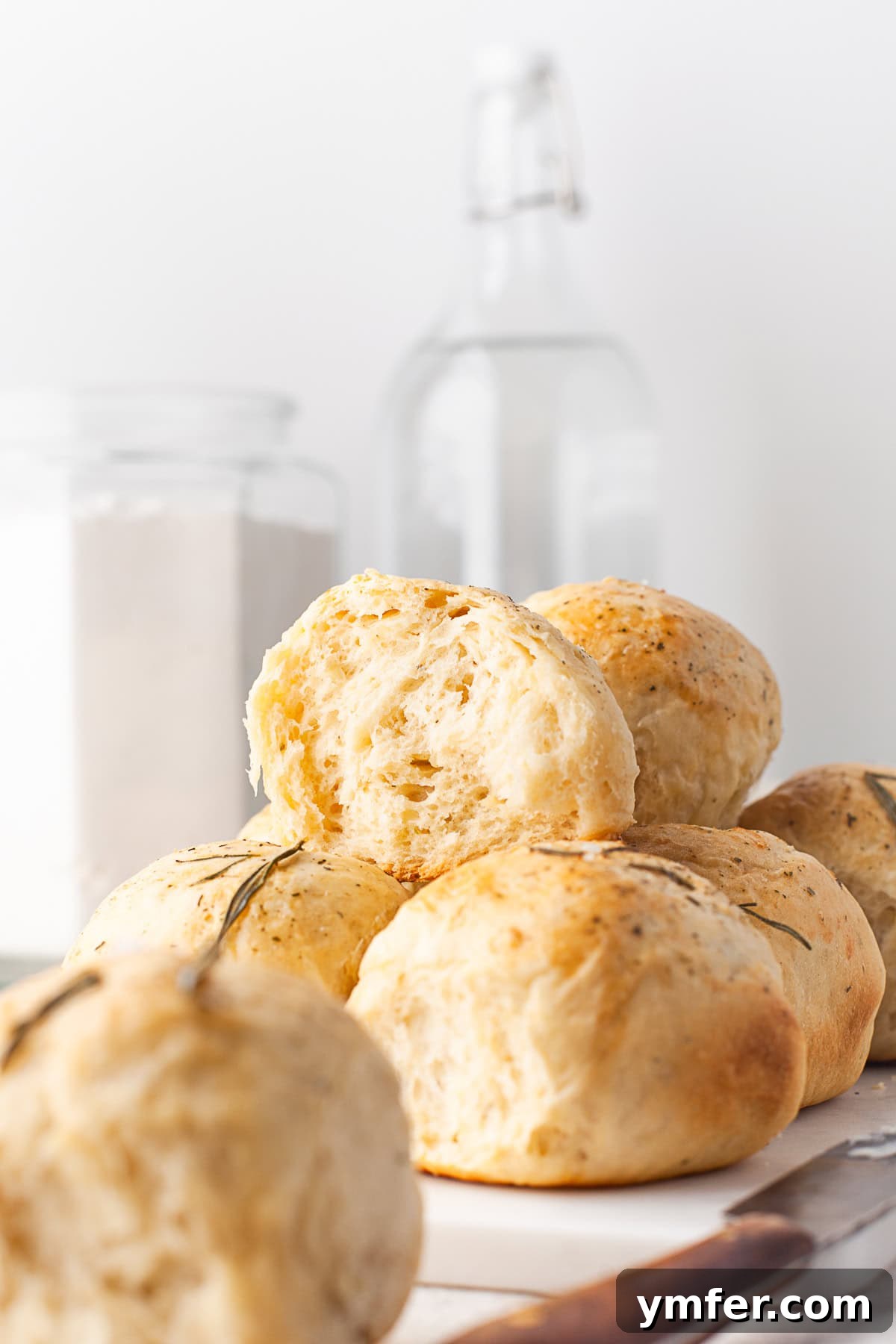 Warm Garlic Herb Rolls 8 A freshly baked Garlic Herb Dinner Roll, cut in half to reveal its fluffy, tender interior, showcasing the garlic and rosemary.