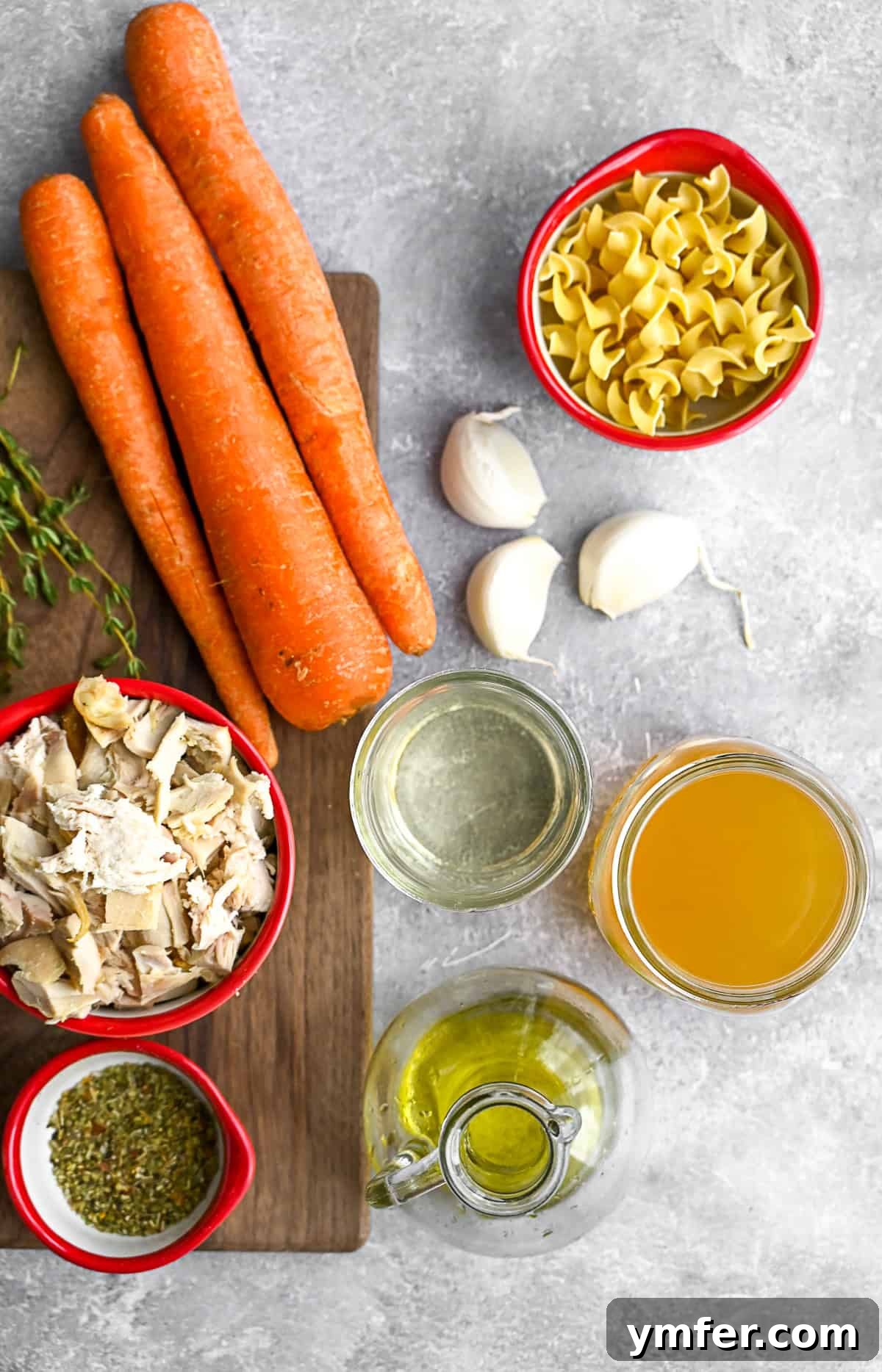 Turkey Noodle Soup Revival 3 Fresh ingredients for Leftover Turkey Noodle Soup laid out on a rustic wooden table, including sliced carrots, minced shallots, fresh thyme, and dried spices.
