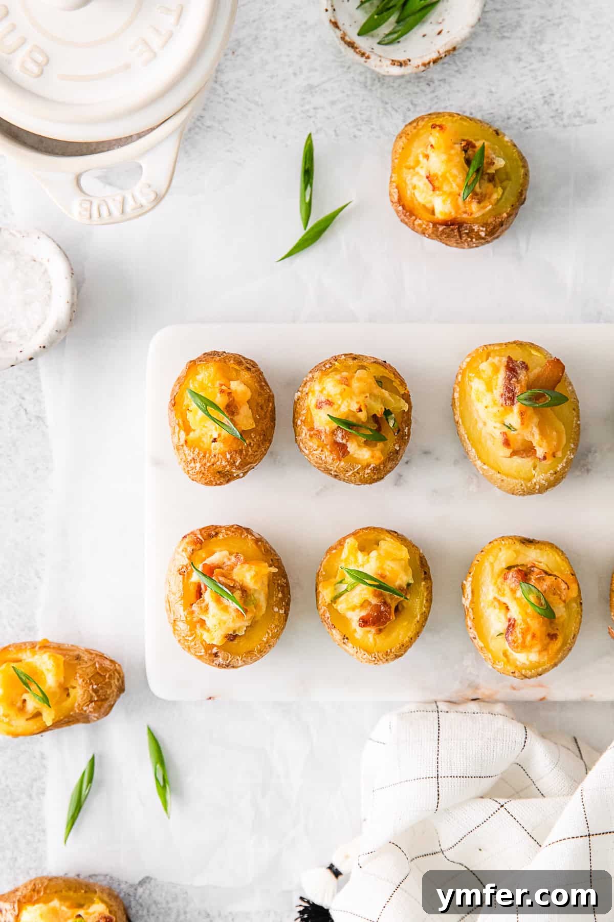 Tiny Tater Toppers 2 A serving board filled with golden-brown Mini Loaded Baked Potatoes, garnished with fresh chives, ready to be enjoyed.