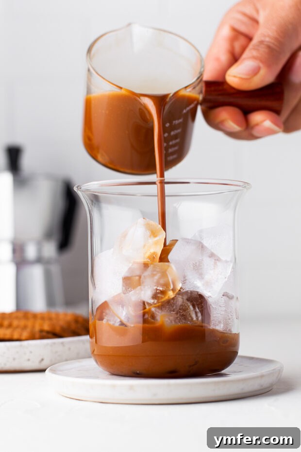 Spiced Biscoff Cookie Butter Latte 5 Cookie butter being stirred into hot espresso in a glass.