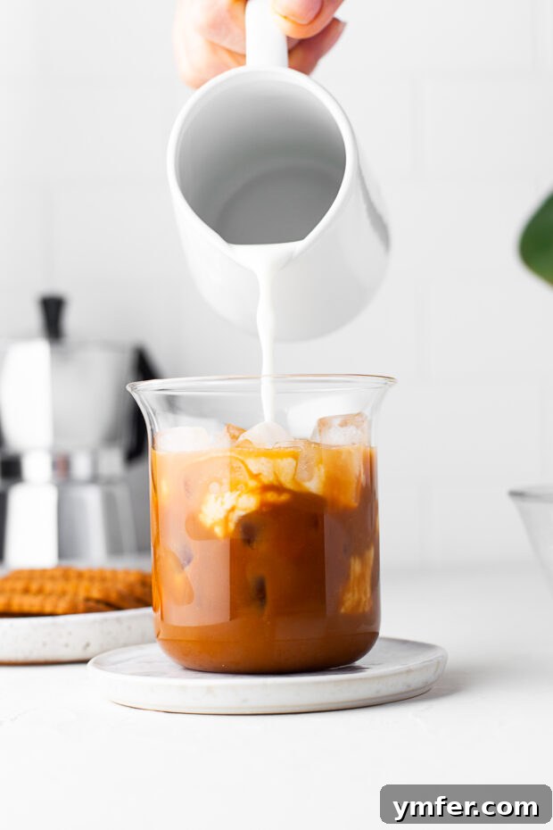 Spiced Biscoff Cookie Butter Latte 6 Cookie butter cold foam being poured over an iced latte.