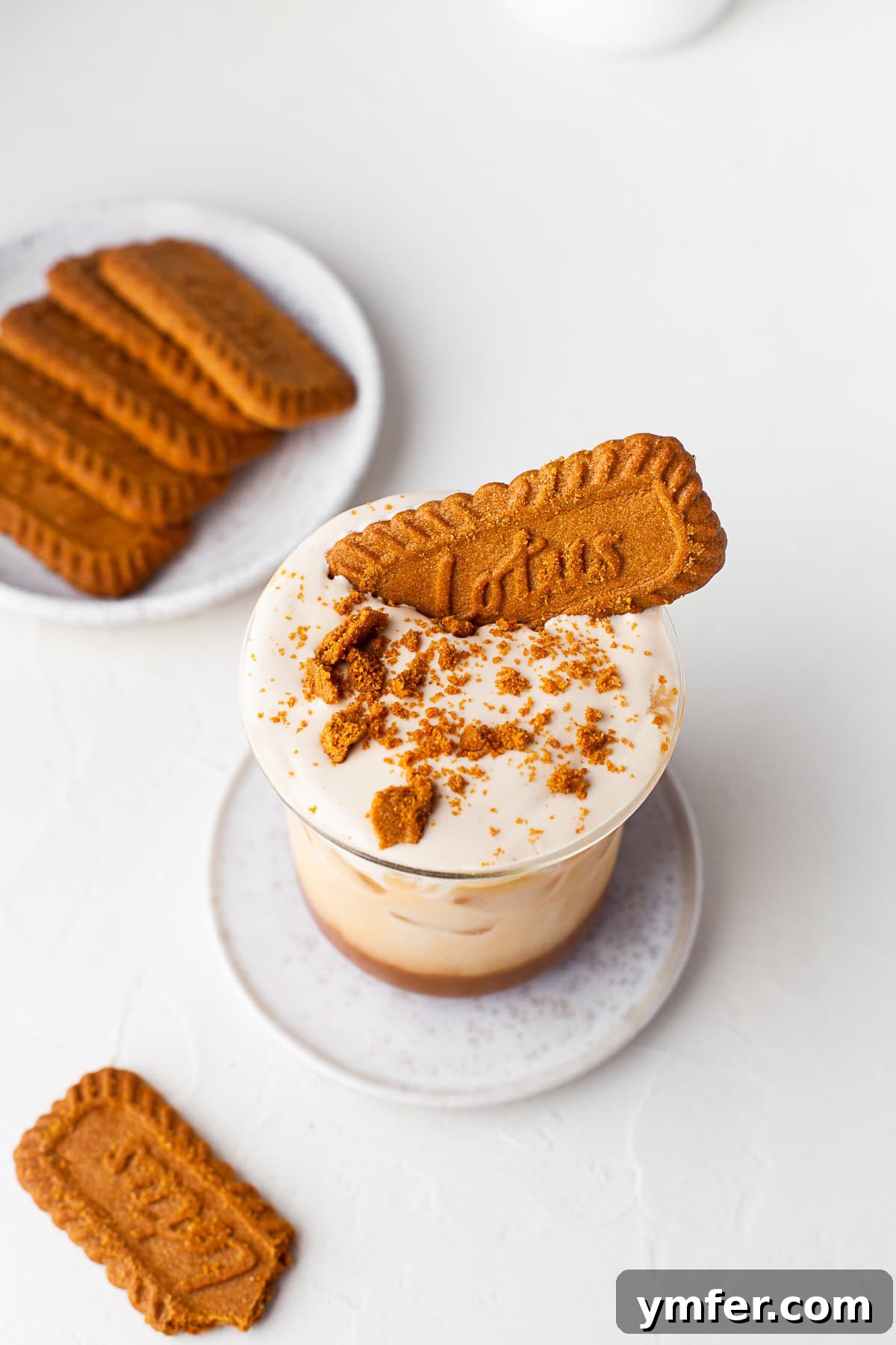 Spiced Biscoff Cookie Butter Latte 7 A hand holding an iced cookie butter latte, with a warm, inviting backdrop.