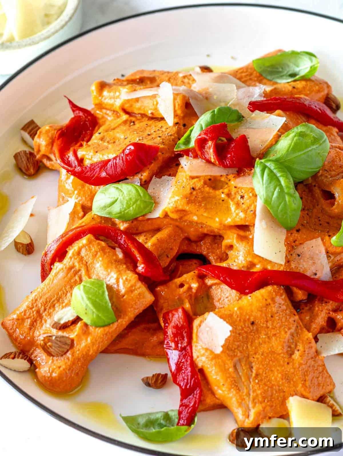 Vibrant Red Pepper Pasta 2 Close-up of creamy roasted red pepper pasta in a bowl, garnished with fresh basil.