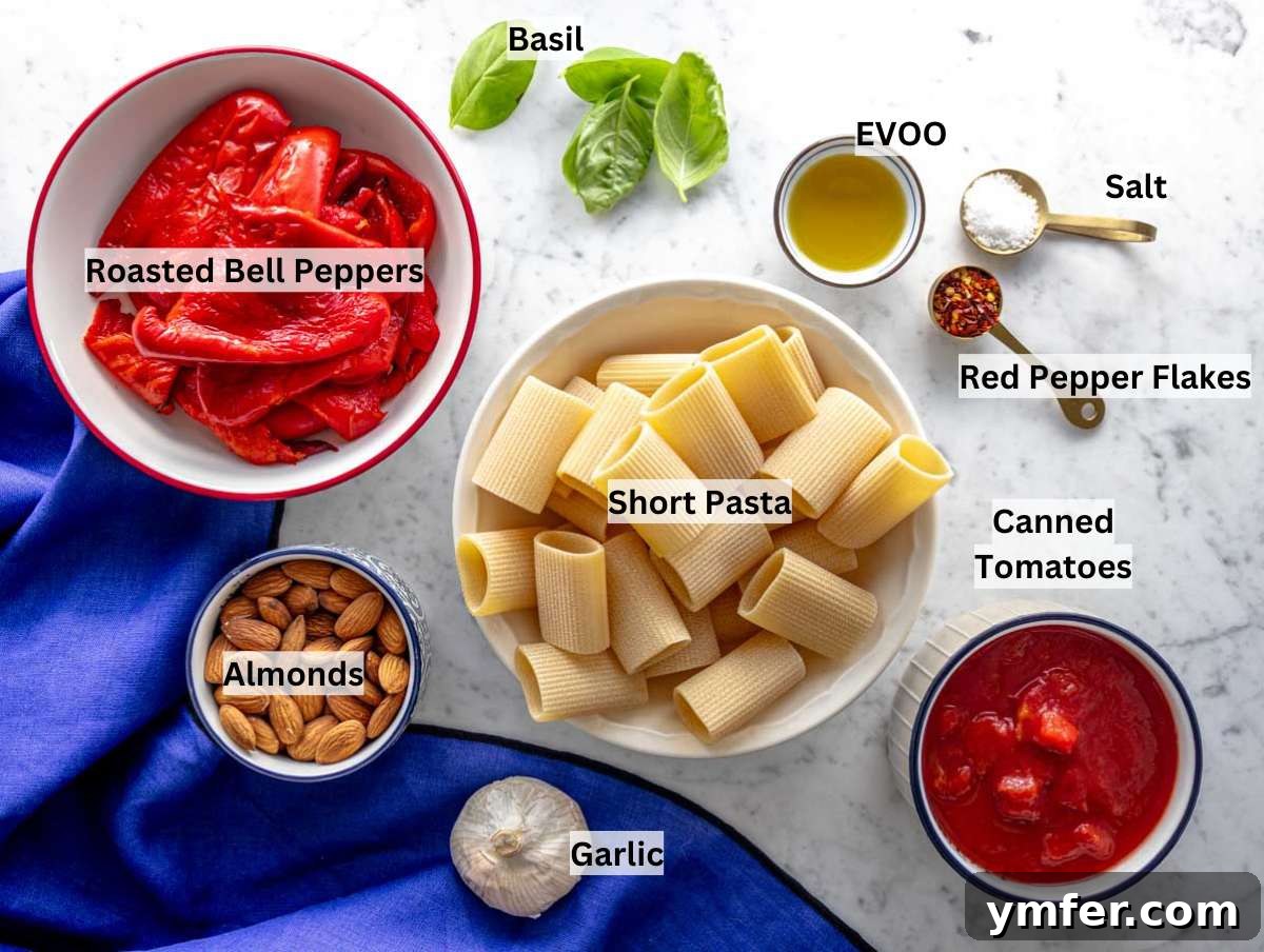 Vibrant Red Pepper Pasta 3 A vibrant selection of ingredients for red pepper pasta laid out on a marble countertop, including roasted red peppers, tomatoes, almonds, and fresh herbs.
