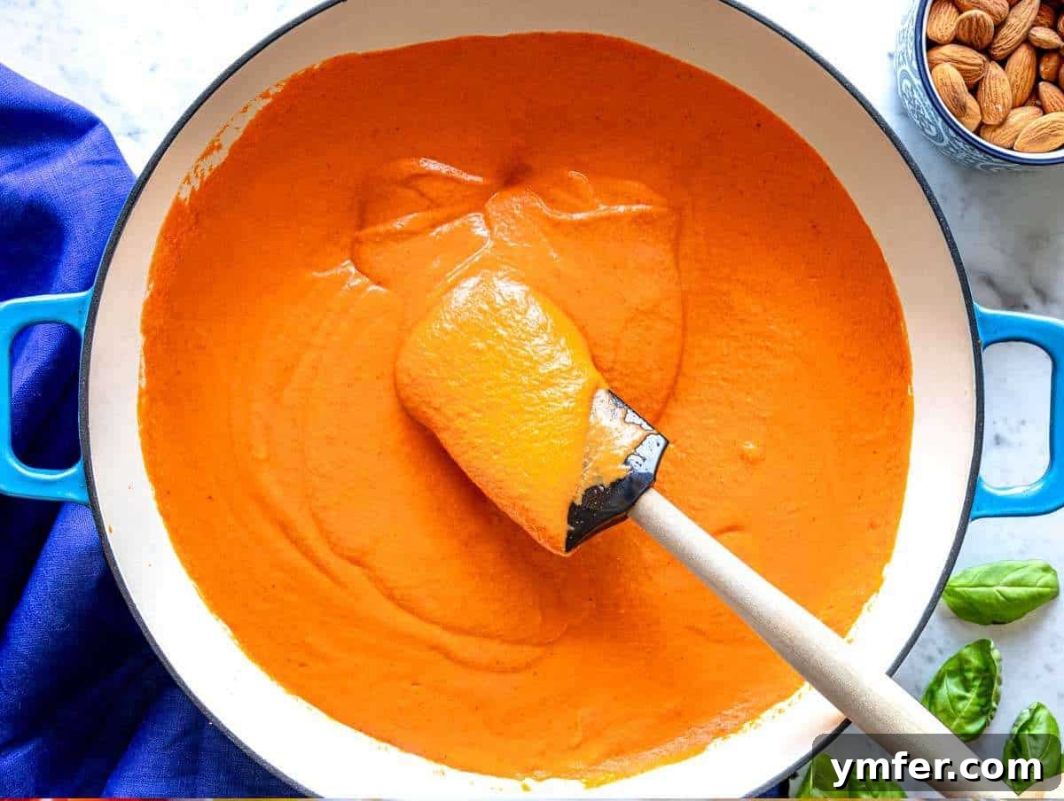 Vibrant Red Pepper Pasta 6 Step 2: Rich red pepper sauce simmering gently in a large skillet on the stovetop, releasing its aromatic steam.