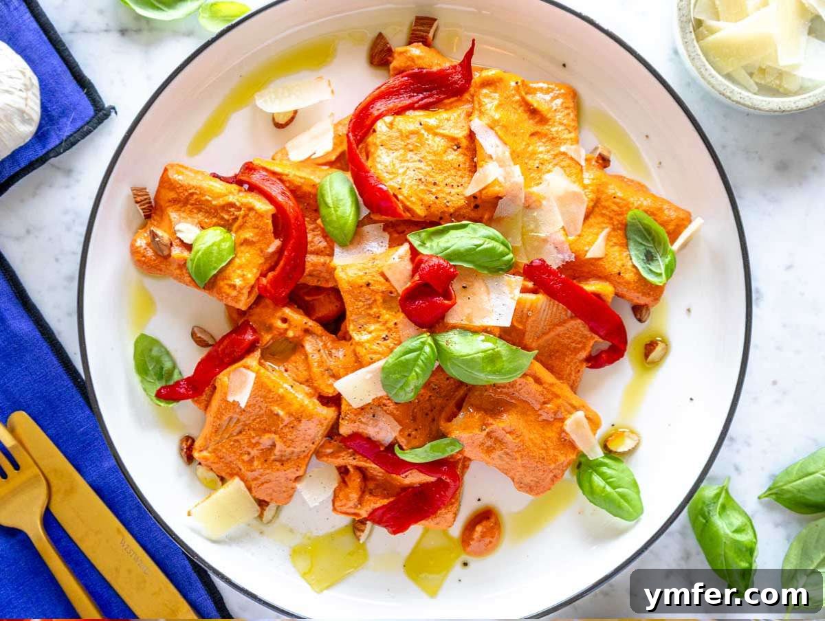 Vibrant Red Pepper Pasta 8 Step 4: A beautifully plated serving of red pepper pasta, artfully garnished with shaved parmesan, fresh basil, and crunchy almonds.