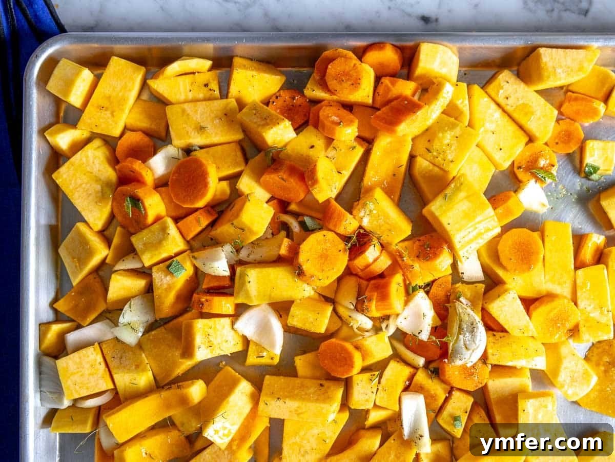 Velvet Butternut Comfort 6 Chopped butternut squash, carrots, onion, garlic, and herbs on a baking tray, ready for roasting