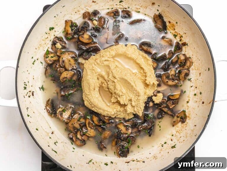 Adding hummus to sautéed mushrooms in a pan