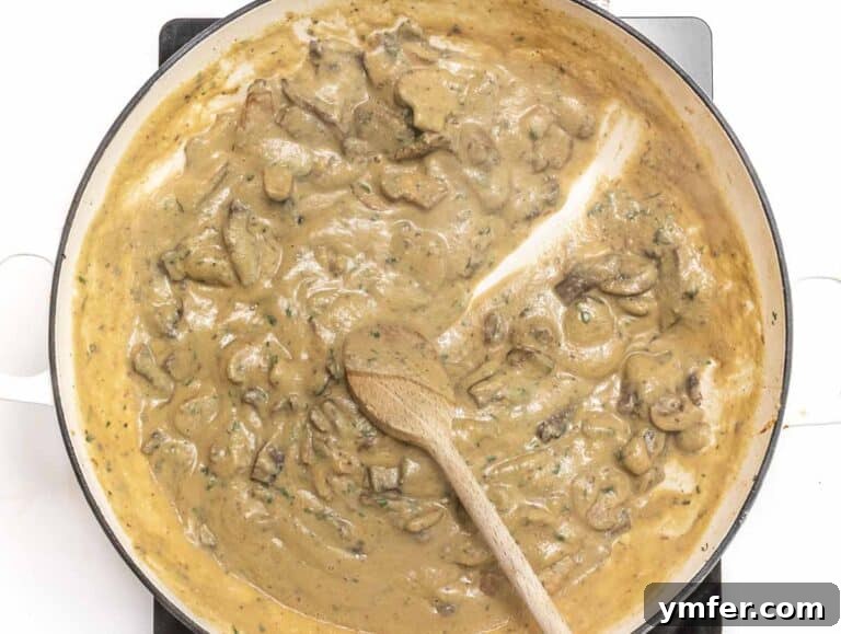 Mixing the creamy hummus sauce with mushrooms in a skillet