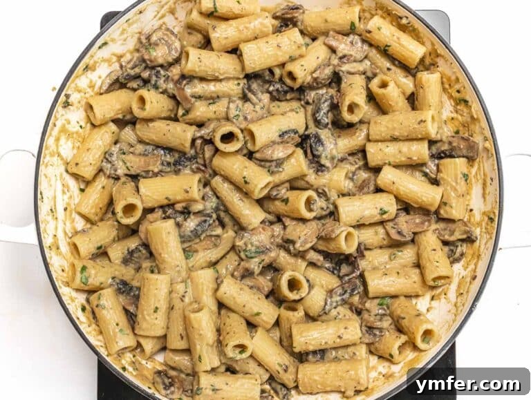 Hummus pasta being tossed in a skillet with the creamy sauce