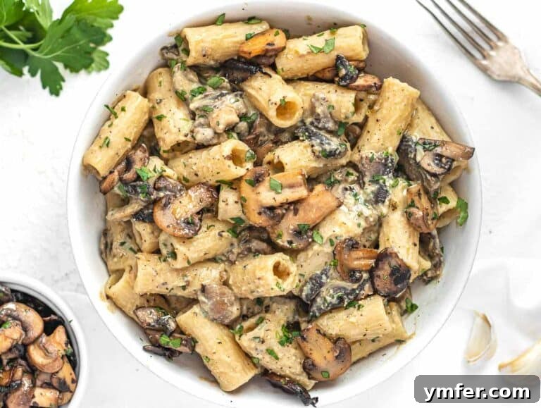 Hummus Pasta in a bowl with a fork, garnished with parsley and pepper