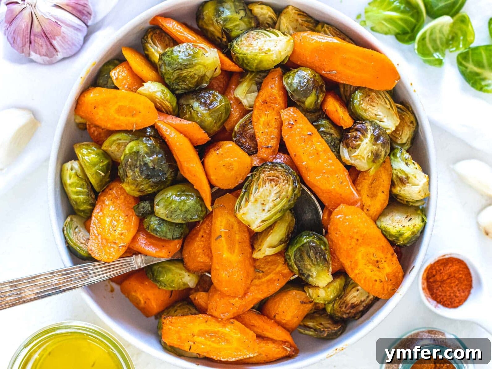Crispy Roasted Brussels Sprouts 14 Roasted carrots and Brussels sprouts in a white bowl with a serving spoon, a vibrant mixed side dish.