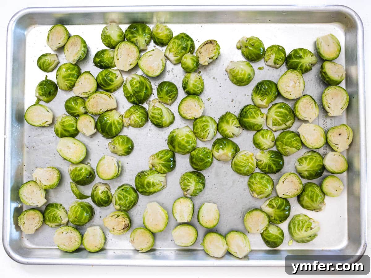 Crispy Roasted Brussels Sprouts 9 Roasted Brussels Sprouts seasoned with olive oil, salt, and pepper on a baking sheet before going into the oven.