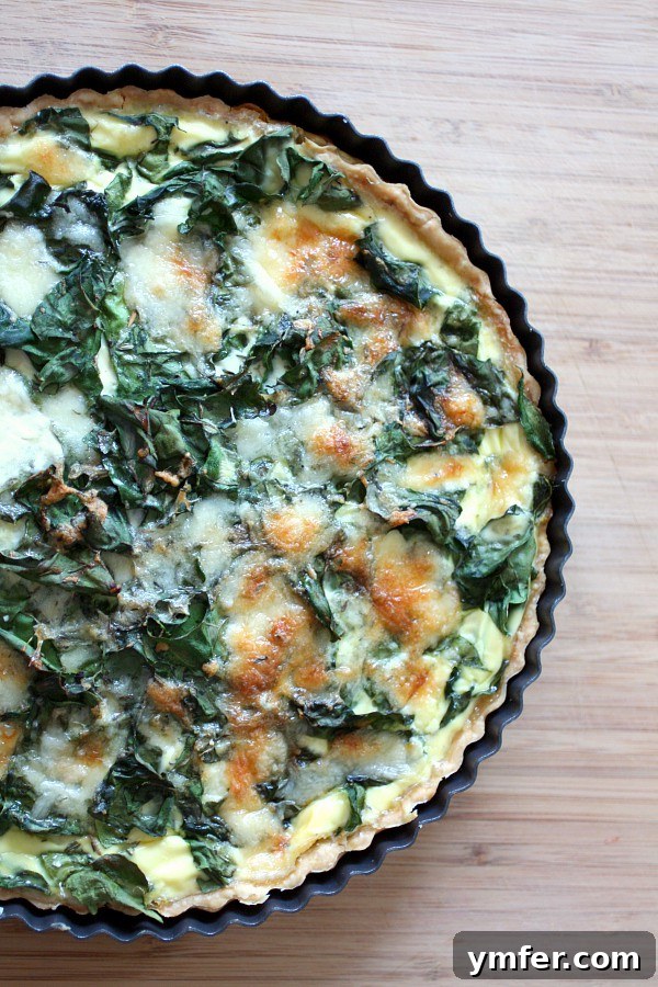 Swiss Chard, Leek and Gruyere Quiche by Nutmeg Nanny Golden-baked Swiss Chard Leek Quiche in a tart pan, ready to be served.