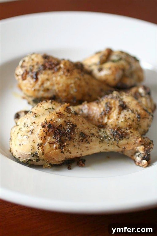Crispy Golden Chicken Legs 2 Crispy, golden-brown roasted chicken legs seasoned with Italian herbs on a white plate, ready to serve alongside fresh greens.