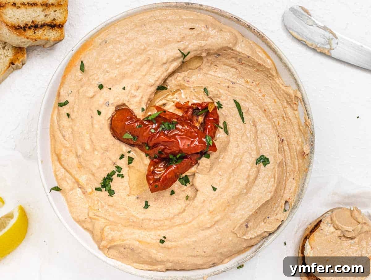 Bowl of reddish-orange sun-dried tomato cream cheese, garnished with fresh basil
