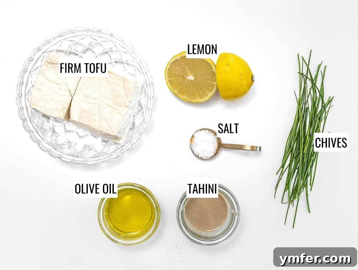 Arrangement of ingredients for tofu cream cheese: firm tofu block, fresh lemons, olive oil, tahini, and a salt shaker