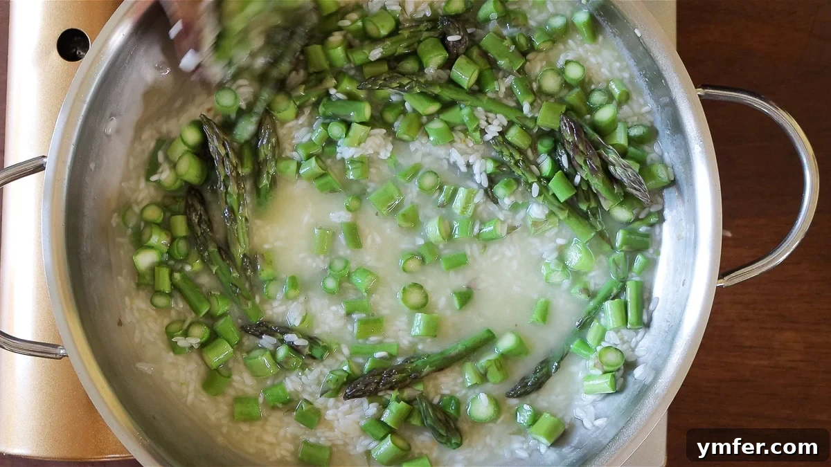 Effortless Plant-Based Risotto 12 Vegetables and vegetable broth being added to risotto rice in a pot.