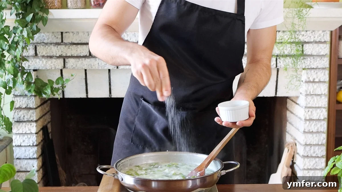 Effortless Plant-Based Risotto 14 Seasoning risotto with salt, adjusting flavor during cooking.