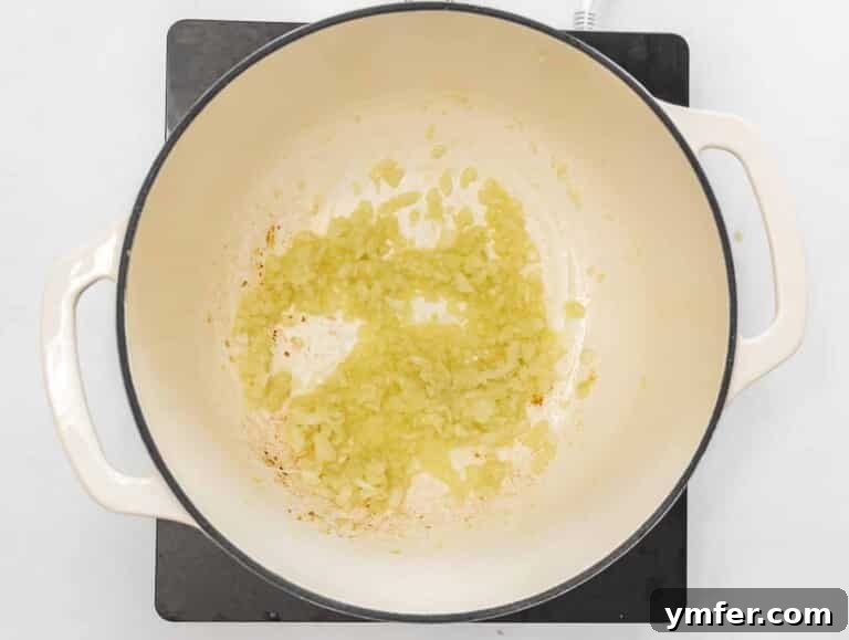 Effortless Plant-Based Risotto 19 Onions and risotto rice sautéing in a Dutch oven.