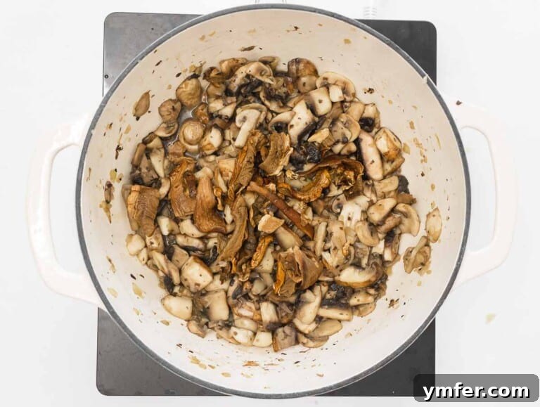 Effortless Plant-Based Risotto 20 Button mushrooms being added to toasted rice in a Dutch oven.