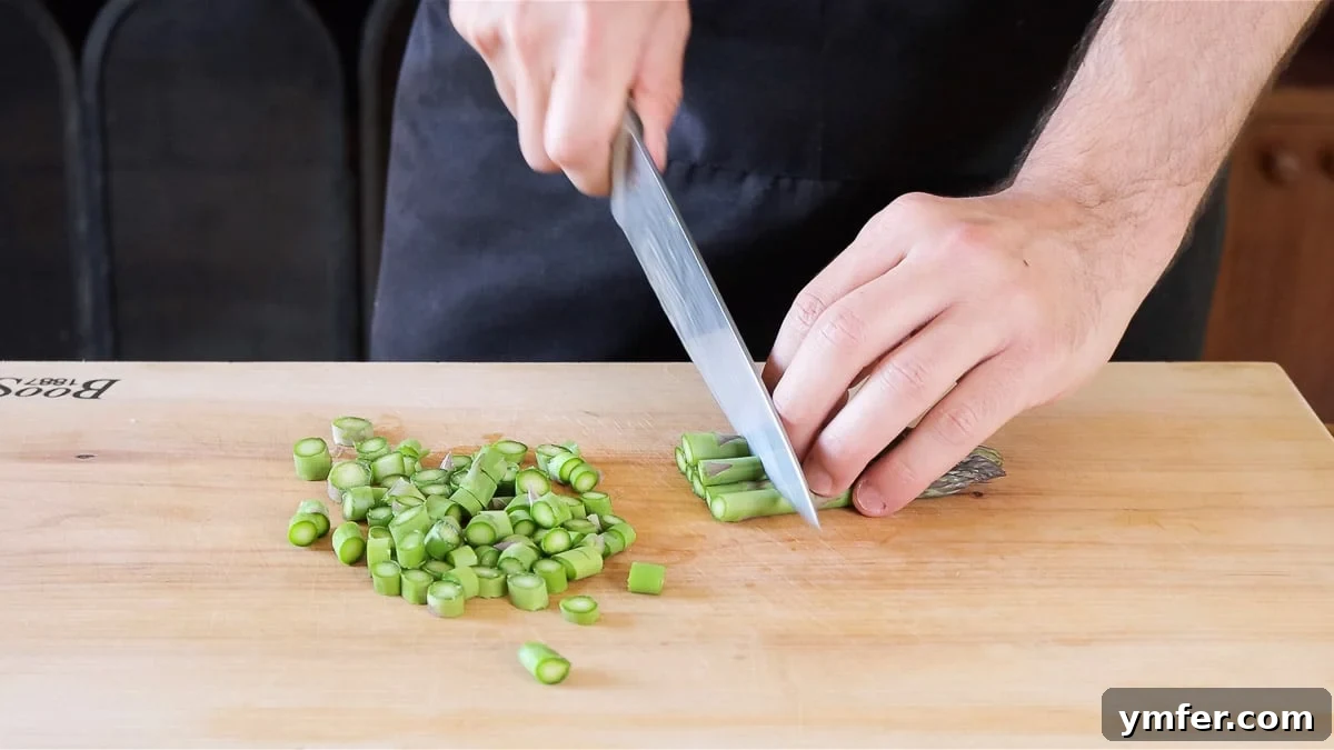 Effortless Plant-Based Risotto 9 Chef meticulously chopping fresh asparagus into small pieces.