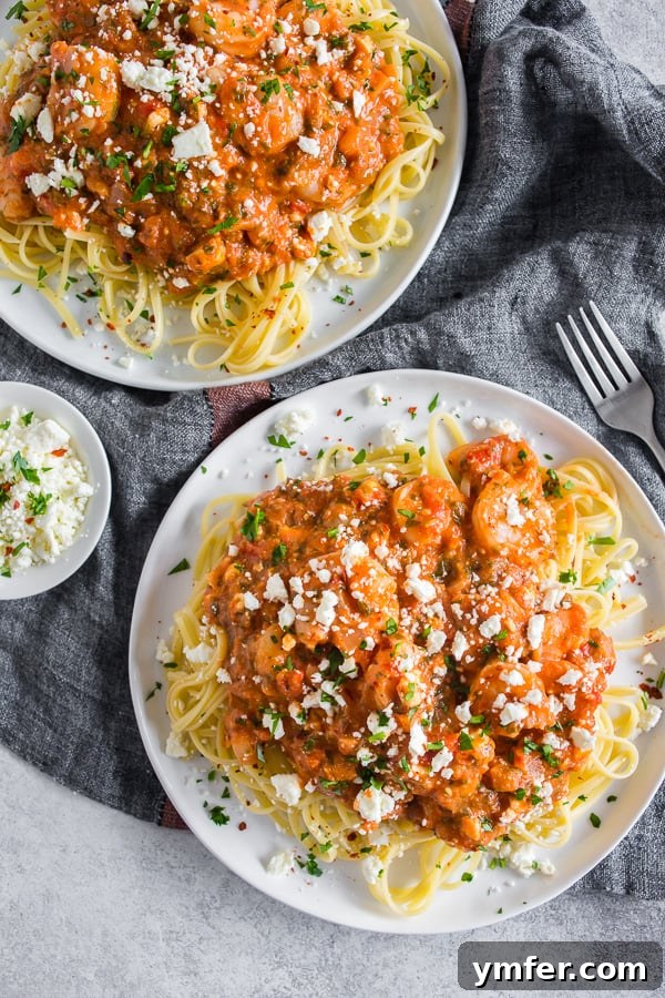 Baked Feta and Shrimp Pasta 2 Two plates of Shrimp Feta Pasta, showcasing the vibrant colors and appealing texture of the dish. The pasta is intertwined with plump shrimp and a rich tomato sauce, generously topped with crumbled feta cheese.