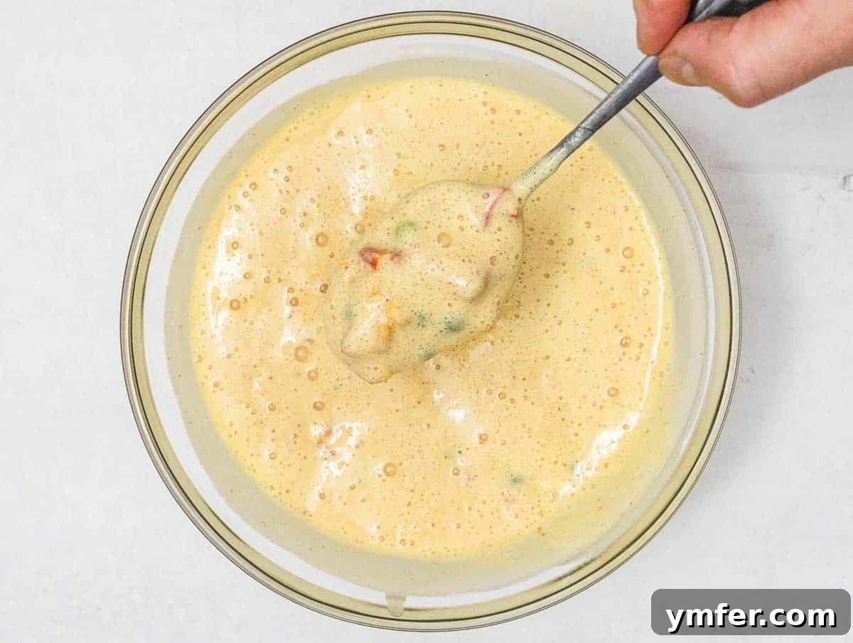 Wholesome Chickpea Egg Muffins 10 Chickpea Muffin batter with veggies and hand holding a spoon