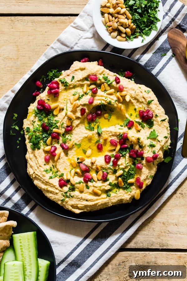 Tahini Free Hummus on a plate topped with parsley, olive oil, and pomegranate seeds. A vibrant, healthy dip for any occasion.