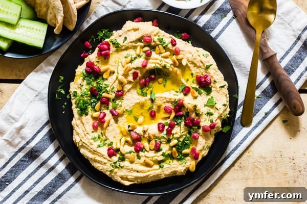 Tahini Free Hummus on a black plate, garnished simply with olive oil and fresh herbs. A minimalist yet inviting presentation.