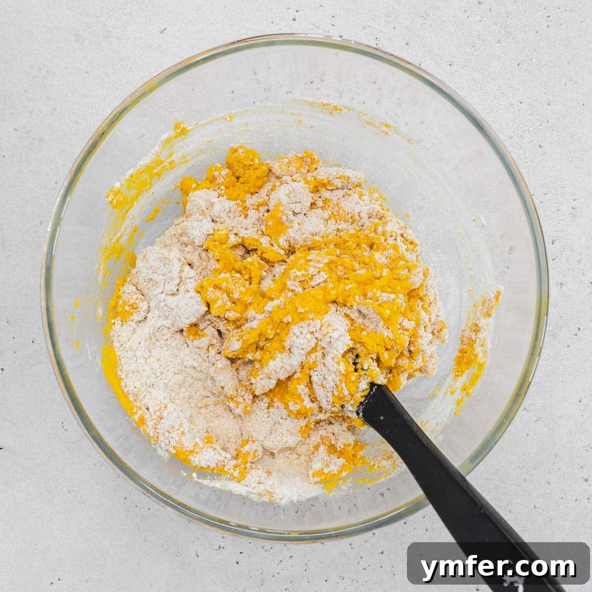 Dolce Carota Cake 10 The process of mixing blended carrots with dry ingredients in a bowl.