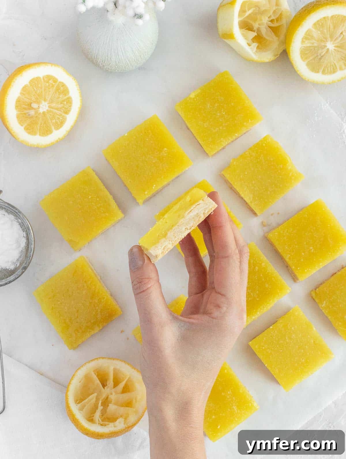 Zesty Plant-Based Lemon Squares 3 A person holding a freshly baked vegan lemon bar, showcasing its golden crust and creamy filling.