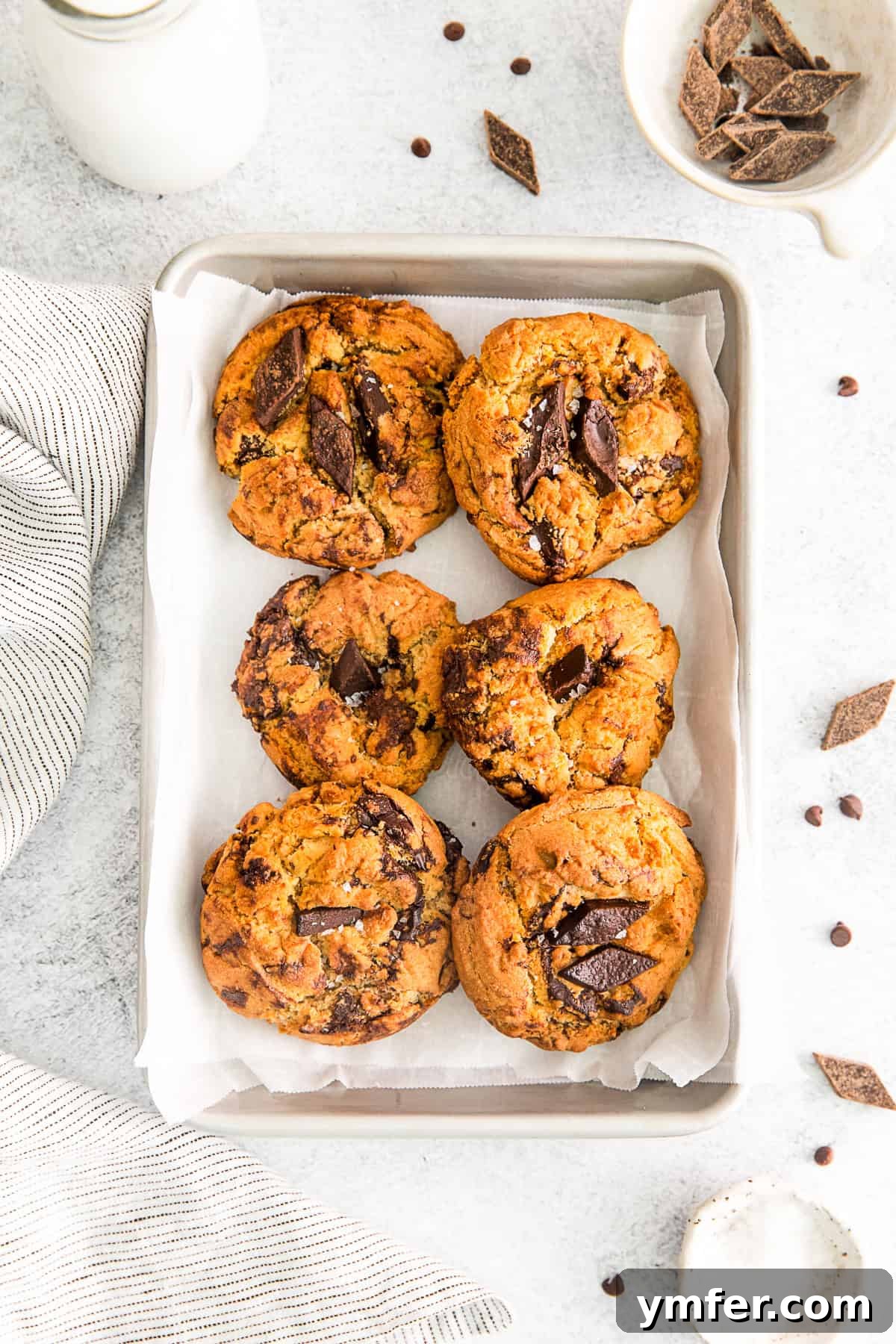 Freshly baked air fryer chocolate chip cookies on a small parchment-lined baking sheet, golden brown and studded with melted chocolate.