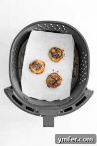 Six balls of air fryer chocolate chip cookie dough placed on parchment paper in an air fryer basket.