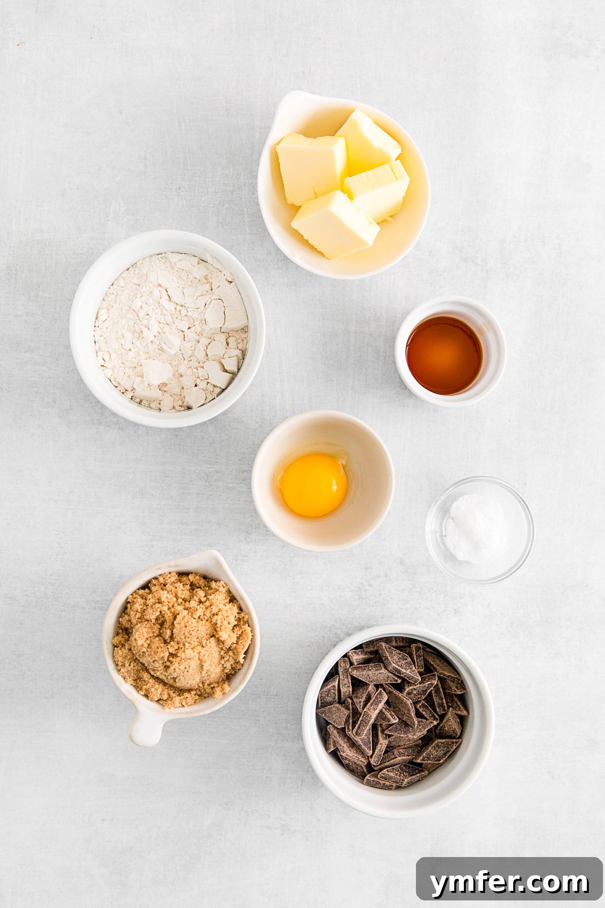 Bowls of essential ingredients for air fryer chocolate chip cookies: melted butter, brown sugar, egg yolk, vanilla extract, all-purpose flour, baking soda, and chocolate chunks.