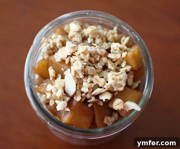 Close-up of a Maple Apple Yogurt Parfait showing distinct layers of yogurt, spiced apples, and granola, ready to eat.