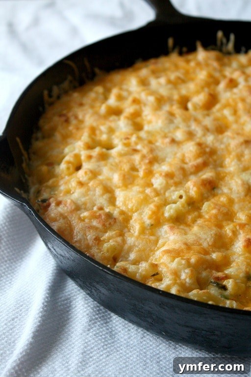 A bubbling skillet of creamy Poblano Macaroni and Cheese, garnished with fresh herbs, ready to be served.