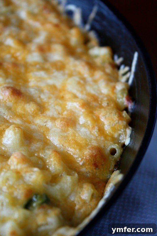 Close-up of Poblano Macaroni and Cheese in a cast iron skillet, showcasing its rich texture and melted cheese pull.
