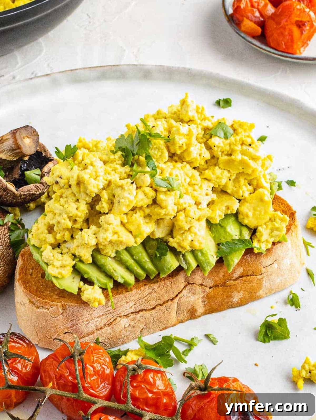 Plant-Powered Scramble 2 Delicious and easy tofu scramble on a piece of toast, garnished with fresh herbs, ready for a healthy breakfast or lunch.