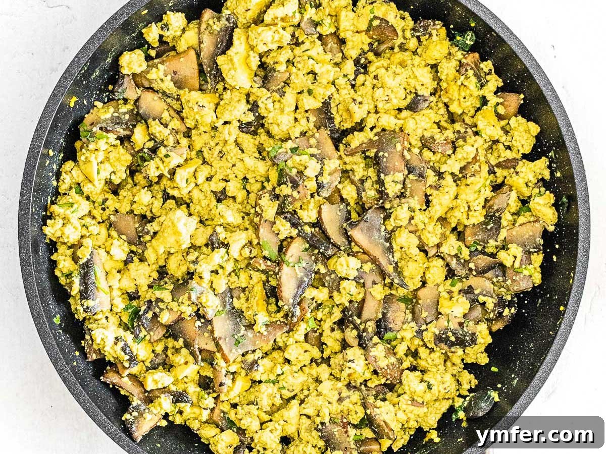 Plant-Powered Scramble 11 Close-up of fluffy scrambled tofu combined with sautéed mushrooms in a pan.