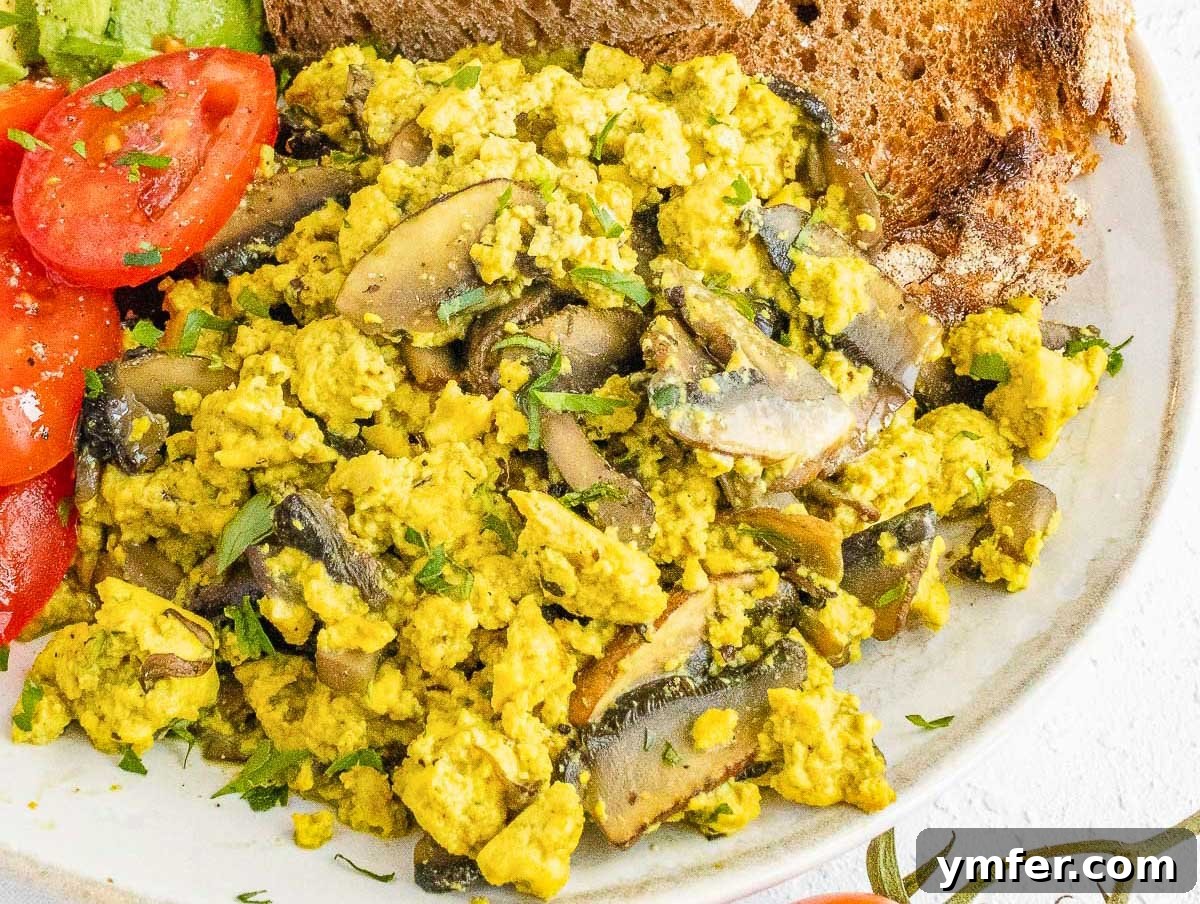 Plant-Powered Scramble 12 A serving of mushroom tofu scramble on a plate, garnished with fresh herbs.