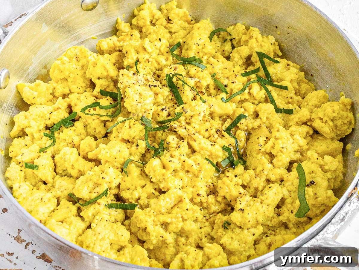 Plant-Powered Scramble 3 Tofu scramble sizzling in a non-stick pan, ready to be seasoned and served.
