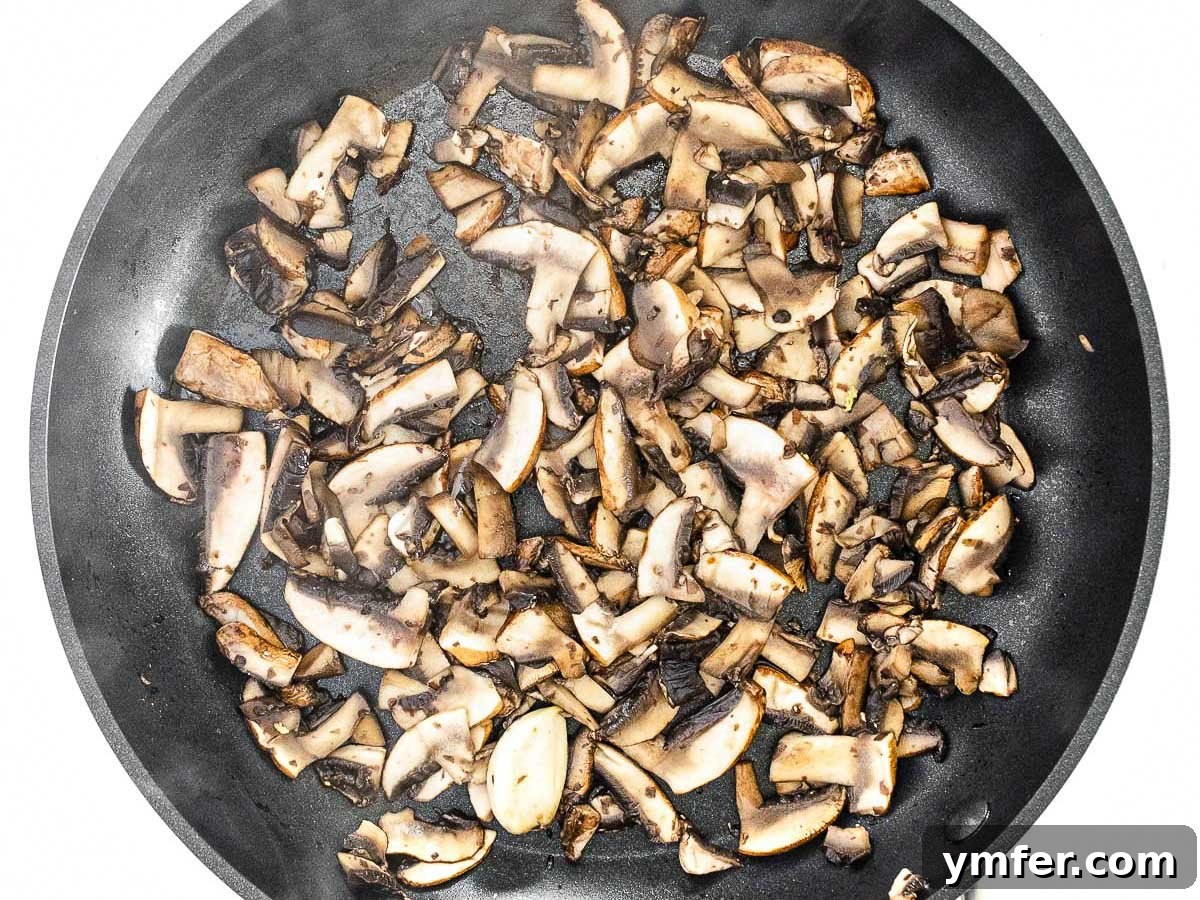 Plant-Powered Scramble 10 Sliced mushrooms browning in a pan, releasing their moisture and caramelizing for a rich flavor.