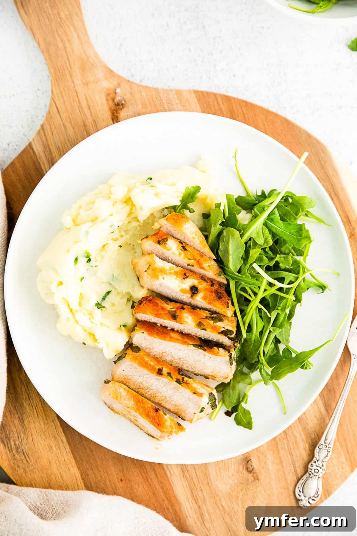 Herbed Marinated Grilled Pork Chop on a plate with mashed potatoes and salad. 