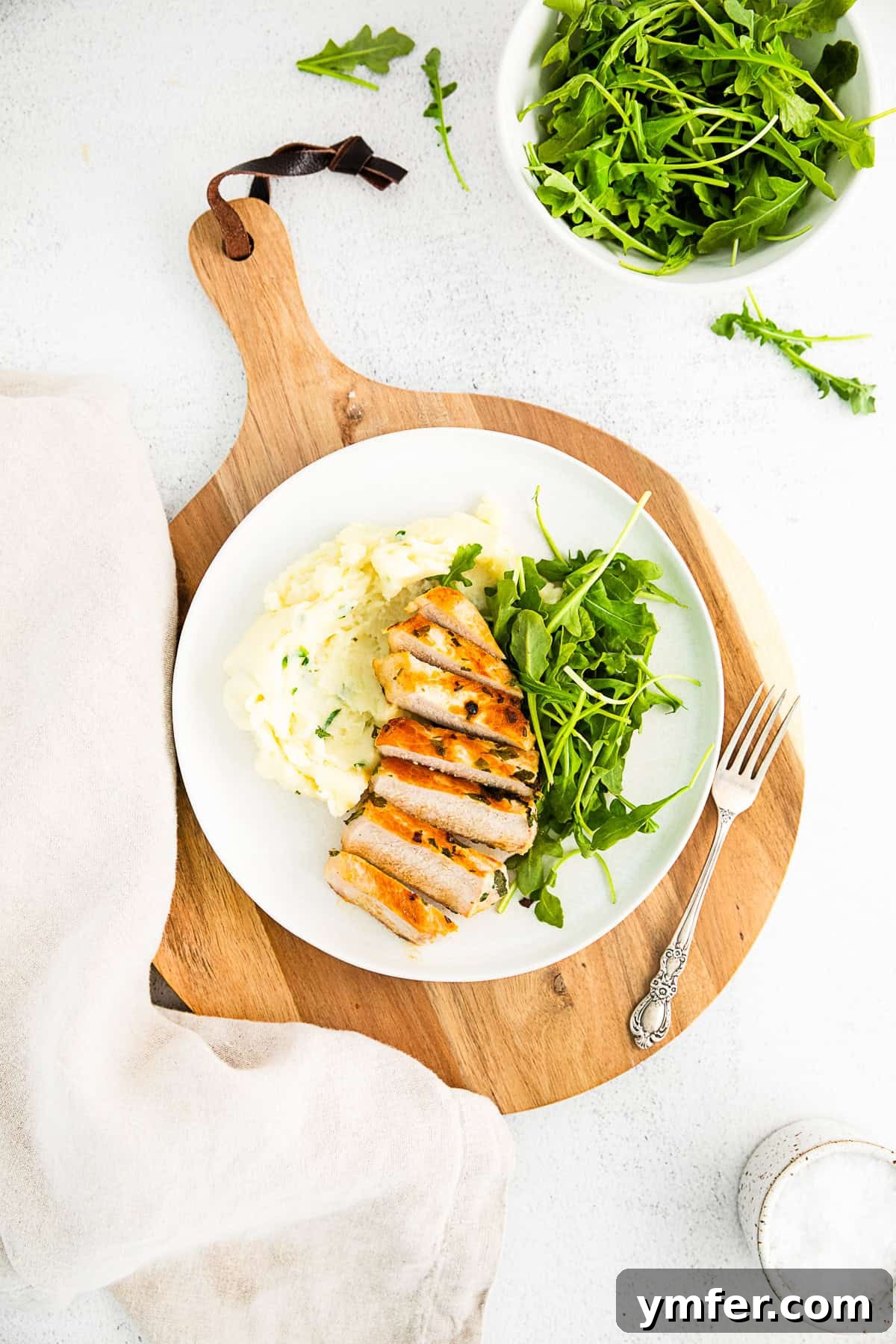 Grilled pork chops served on a white plate with a fork. 
