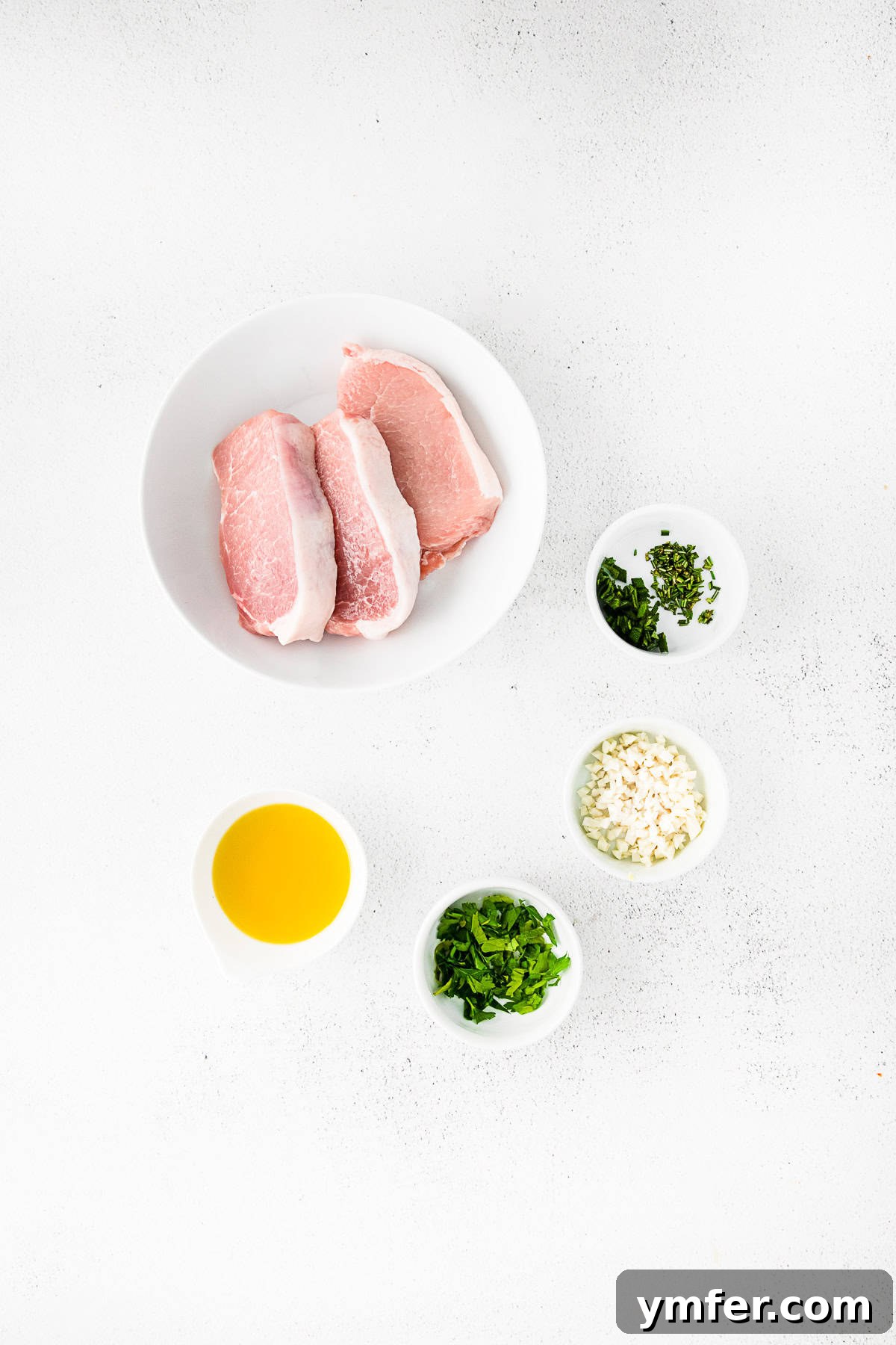 pork chops, olive oil, herbs, and garlic on a table. 