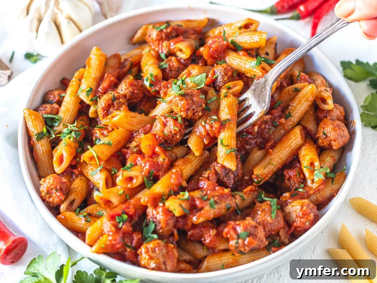 35 Stress-Free Dinner Recipes 5 Penne Arrabbiata in a white bowl with a silver fork piercing the pasta, showcasing its rich red sauce