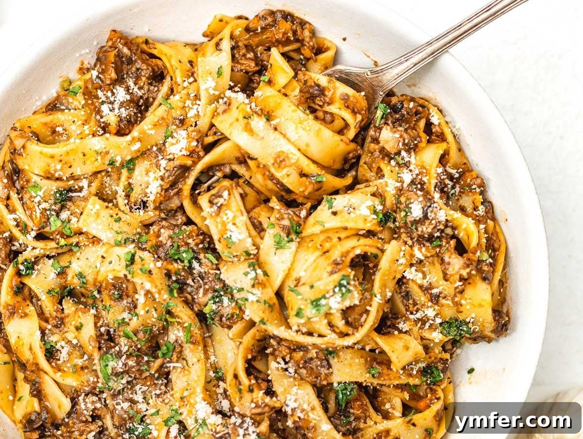 35 Stress-Free Dinner Recipes 6 Hearty Mushroom Bolognese topped with vegan parmesan and a fork ready to serve