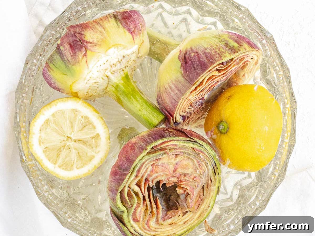 Cleaned artichokes soaking in a bowl of cold lemon water to prevent browning.